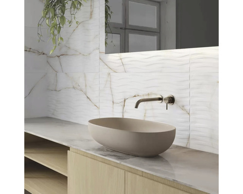 Koupelna s umyvadlem na desku, vodovodní baterií a obkladem stěn s mramorovým vzhledem.