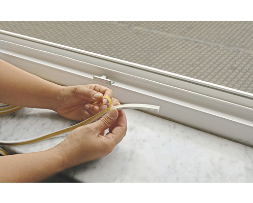 Osoba odstraňuje ochrannou fólii z těsnicí pásky pro renovaci oken