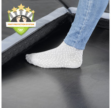 Detailní záběr trampolíny se systémem ochrany nohou a osoby v ponožkách.