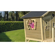 Dítě si hraje v dřevěném domečku s oknem na zahradě.