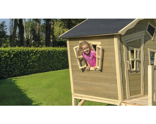 Dítě si hraje v dřevěném domečku s oknem na zahradě.