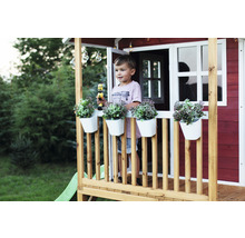 Hrací domek s chlapcem, truhlíky a hračkami na verandě v zahradě