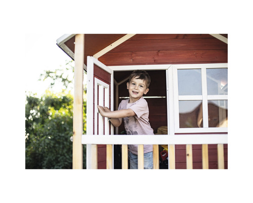 Chlapec si hraje v dřevěném hracím domku s oknem a dveřmi