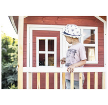 Dítě před dřevěným hracím domkem s oknem a plotem