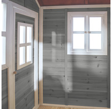 Vnitřní pohled na hrací domek s šedě natřenými dřevěnými stěnami a bílými okenními rámy