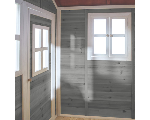 Vnitřní pohled na hrací domek s šedě natřenými dřevěnými stěnami a bílými okenními rámy