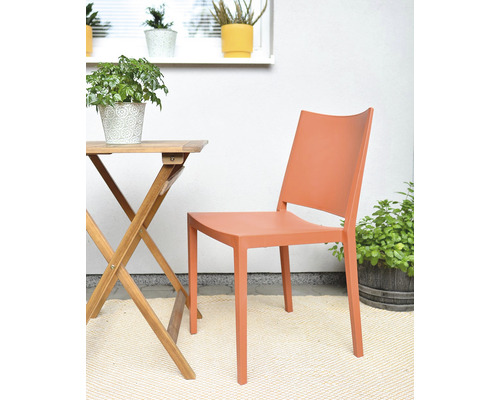 Plastová zahradní židle vedle dřevěného stolu na terase