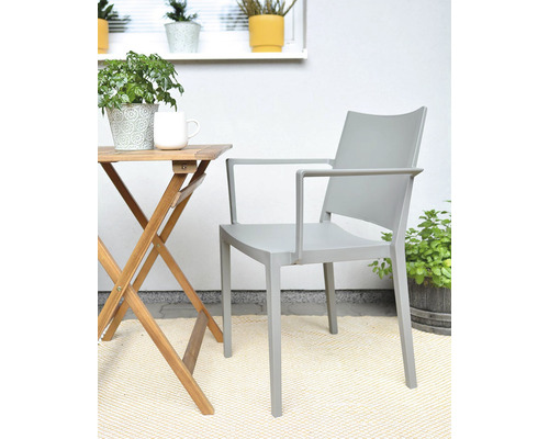 Šedá zahradní židle s područkami vedle dřevěného stolu