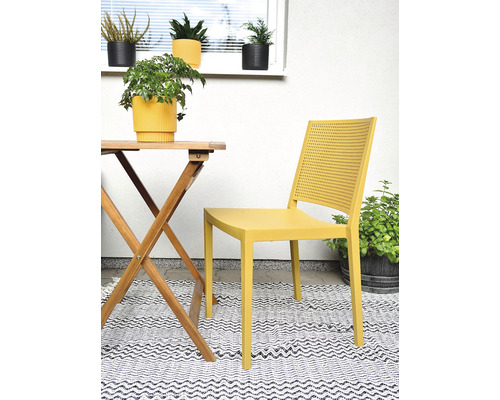 Scéna s dřevěným zahradním stolem, žlutou zahradní židlí a venkovním kobercem