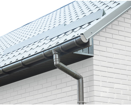 Střešní žlab na domě s cihlovou zdí a kovovou střechou