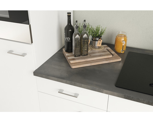 Kuchyňské zátiší s prkénky na krájení, lahvemi na olej, bylinkami a varnou deskou na pracovní desce