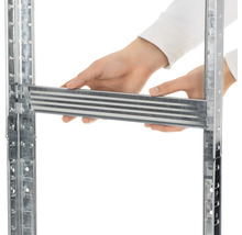 Detailní pohled na osobu vkládající kovový prvek do regálového systému