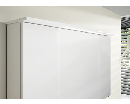 Detailní záběr bílé šatní skříně s nástavným světlem.