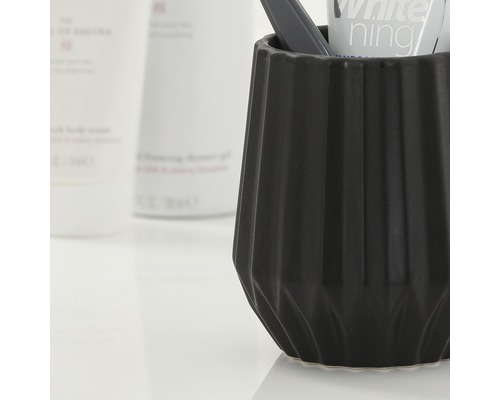 Černý kelímek na zubní kartáčky se zubním kartáčkem a zubní pastou