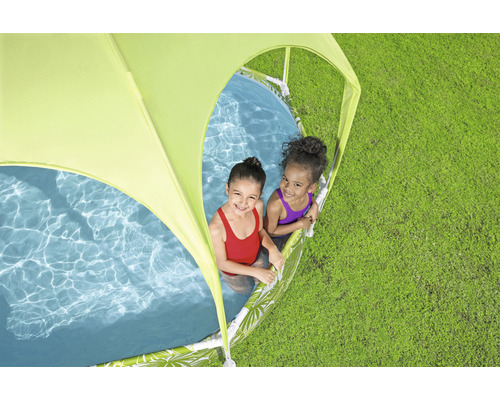 Dvě děti si hrají v bazénku se sluneční ochranou na trávníku.