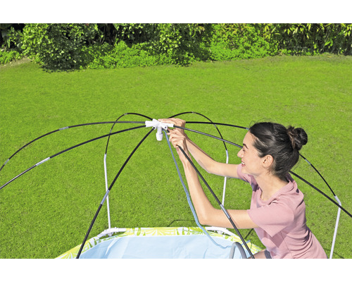 Žena staví v zahradě bazének s ochranou proti slunci.