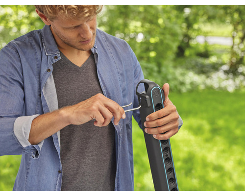 Muž montuje zahradní hadicový vozík pomocí montážního nástroje na zahradě.