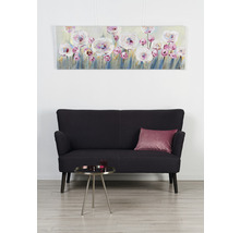 Obývací pokoj s plátěným obrazem s květinovým motivem, černou pohovkou a odkládacím stolkem