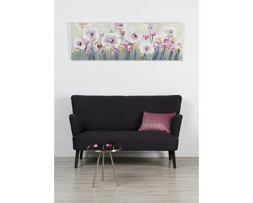 Obývací pokoj s plátěným obrazem s květinovým motivem, černou pohovkou a odkládacím stolkem