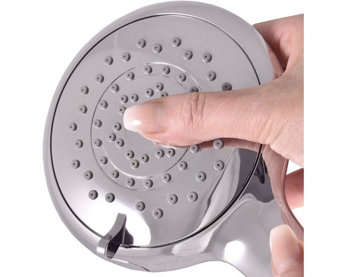 Ruka čistí trysky sprchové hlavice.