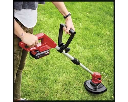 Osoba obsluhuje vyžínač na zahradě.
