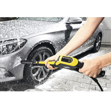 Osoba čistí auto vysokotlakým čističem.