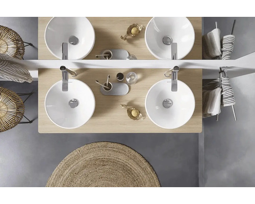 Pohled shora na koupelnu se dvěma umyvadly, vodovodními bateriemi, doplňky a kulatým kobercem