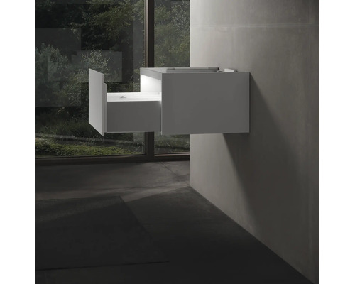 Bílá skříňka pod umyvadlo s otevřenou zásuvkou namontovaná na zdi