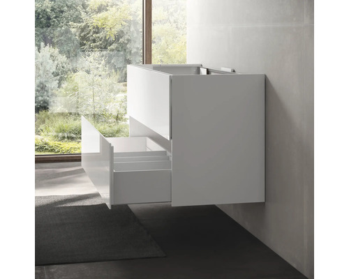 Bílá skříňka pod umyvadlo s otevřenými zásuvkami namontovaná na stěně koupelny