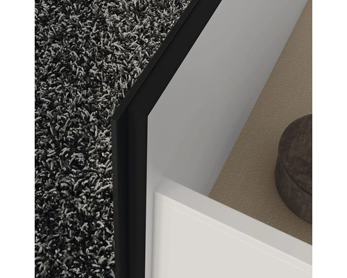 Detailní záběr rohu koupelny s kobercem, skříňkou pod umyvadlo a policí