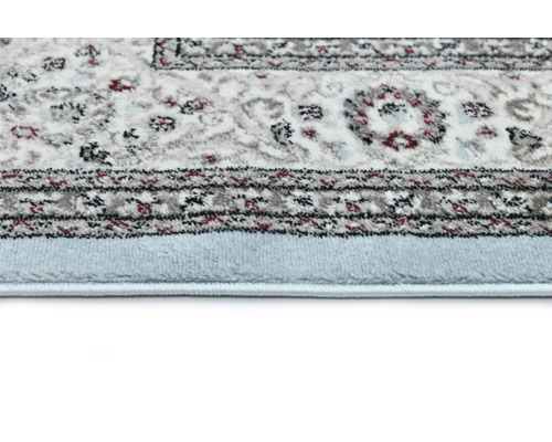 Detailní pohled na koberec s tradičním vzorem a světle modrým okrajem