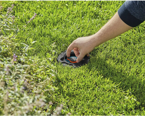 Osoba nastavuje zapuštěný zavlažovač trávníku v trávníku.