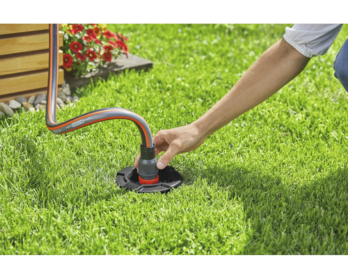 Osoba připojuje zahradní hadici k vodovodní přípojce na zahradě