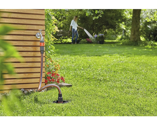 Zahradní scéna s vodovodním kohoutkem, zahradní hadicí a zavlažovačem trávníku pro zavlažování