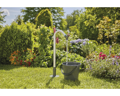 Zahradní scéna s kohoutkem a kbelíkem na trávníku