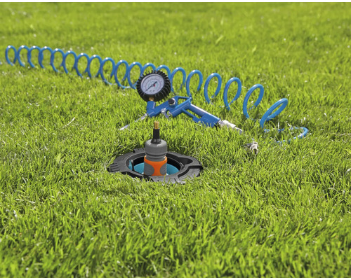 Zavlažovač s pneumatickou pistolí a hadicí na trávníku