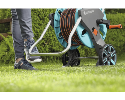 Zahradní scéna s osobou ovládající nohou buben na hadici Gardena