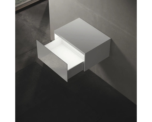 Závěsná skříňka pod umyvadlo s otevřenou zásuvkou v koupelně.