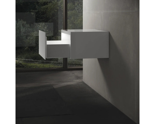 Bílá závěsná skříňka pod umyvadlo s otevřenou zásuvkou v koupelně