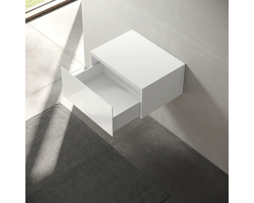 Bílá závěsná skříňka pod umyvadlo s otevřenou zásuvkou v koupelně