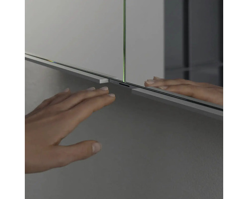 Detailní záběr zrcadlové skříňky s rukou v koupelně