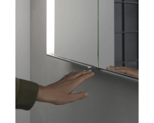 Detailní pohled na zrcadlovou skříňku s rukou, která se jí dotýká