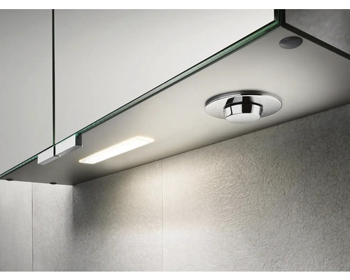 Detailní pohled na zrcadlovou skříňku s osvětlením a kulatým vypínačem