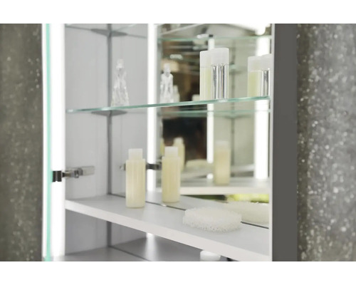 Detailní záběr zrcadlové skříňky se skleněnými policemi a koupelnovými potřebami