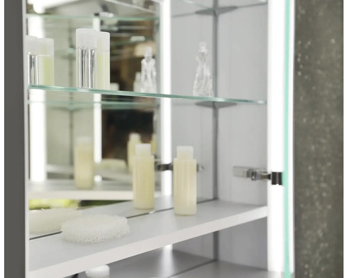 Otevřená zrcadlová skříňka se skleněnými policemi a koupelnovými doplňky
