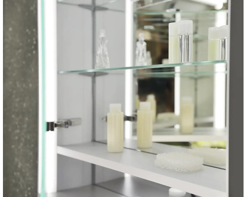 Otevřená zrcadlová skříňka se skleněnými policemi a koupelnovými doplňky