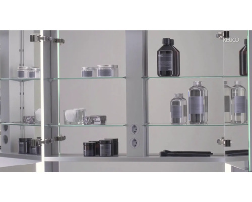 Koupelnová scéna se zrcadlovou skříňkou a různými koupelnovými doplňky na skleněných policích.