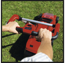 Osoba obsluhuje sekačku na trávu na zahradě.