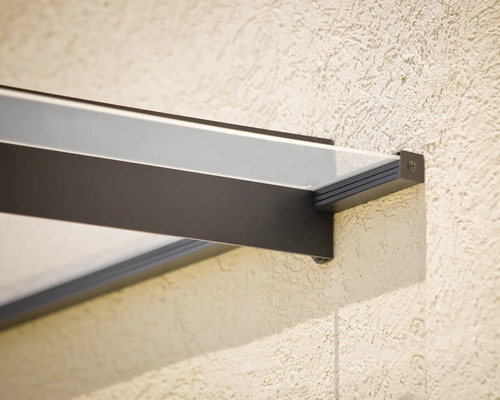 Detailní pohled na stříšku nad vchodovými dveřmi s čirou skleněnou deskou a tmavými rámovými profily.