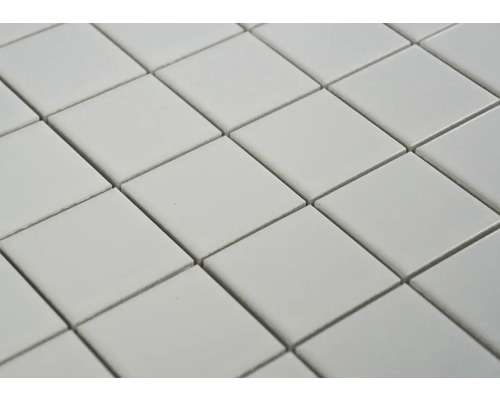 Detailní záběr čtvercových dlaždic uspořádaných diagonálně, vytvářejících opakující se vzor.